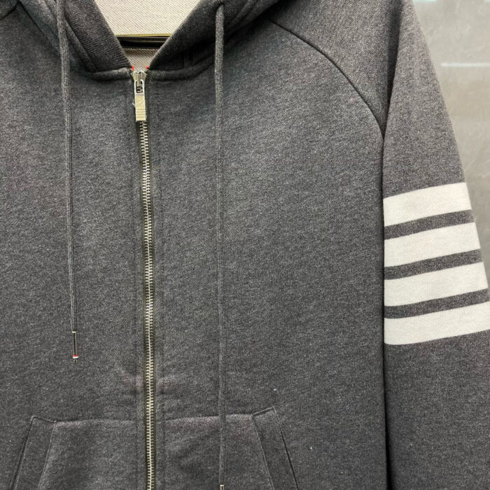 Felpa grigia con zip, cappuccio, strisce bianche e stile sporty casual.