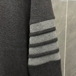 Manica di felpa grigia con bande sportive a rilievo, stile moderno e casual.