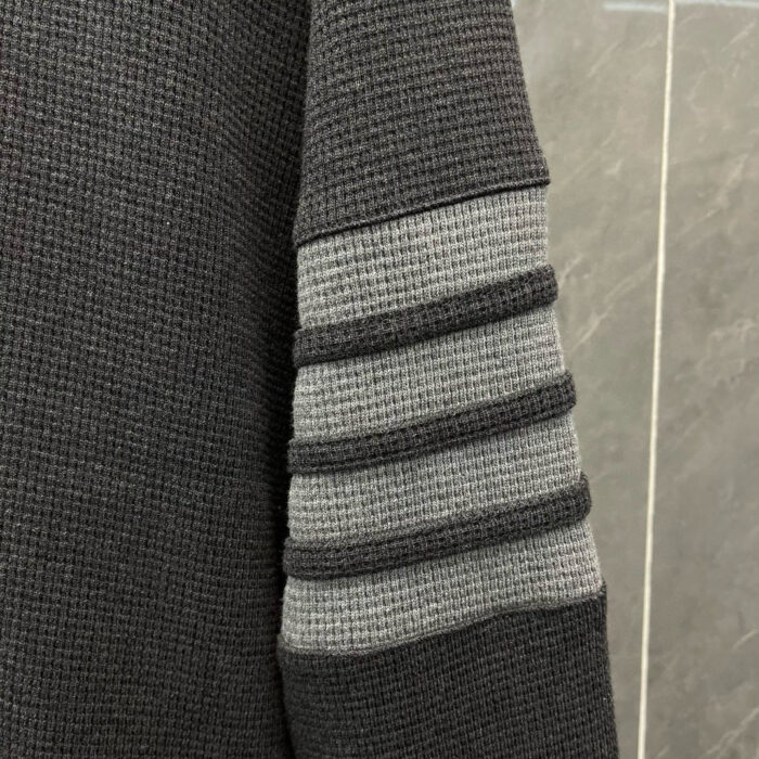 Manica di felpa grigia con bande sportive a rilievo, stile moderno e casual.