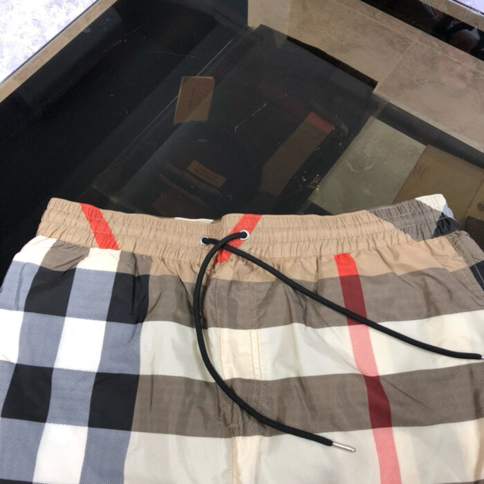 Costume da bagno a quadri beige e nero con elastico e cordino regolabile.