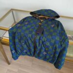 Giacca sportiva a quadri blu e verde con cappuccio e zip, stile moderno e vivace.
