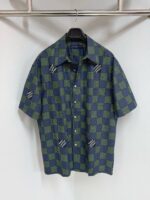 Camicia corta a quadri verde e blu con dettagli artistici, stile casual e moderno.