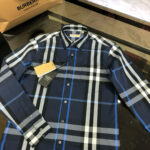 Camicia checkered navy con dettagli blu e shopping bag Burberry, stile elegante e di lusso.