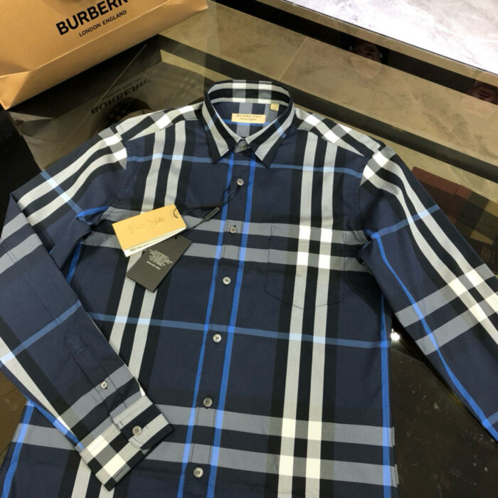 Camicia checkered navy con dettagli blu e shopping bag Burberry, stile elegante e di lusso.