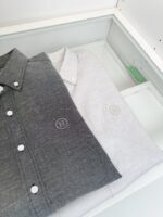 Camicie uomo grigio e bianco con logo, eleganti e ben organizzate in vetrina pulita.
