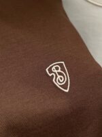 Tessuto marrone cioccolato con ricamo bianco minimalista, perfetto per abbigliamento casual e elegante.