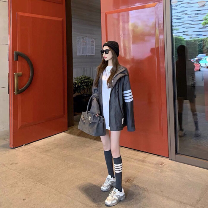 Donna giovane in stile urbano chic davanti a porte rosse moderne.