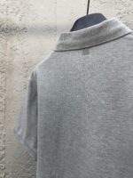 Maglietta polo grigia da dietro, stile classico, tessuto morbido e dettagli minimalisti.