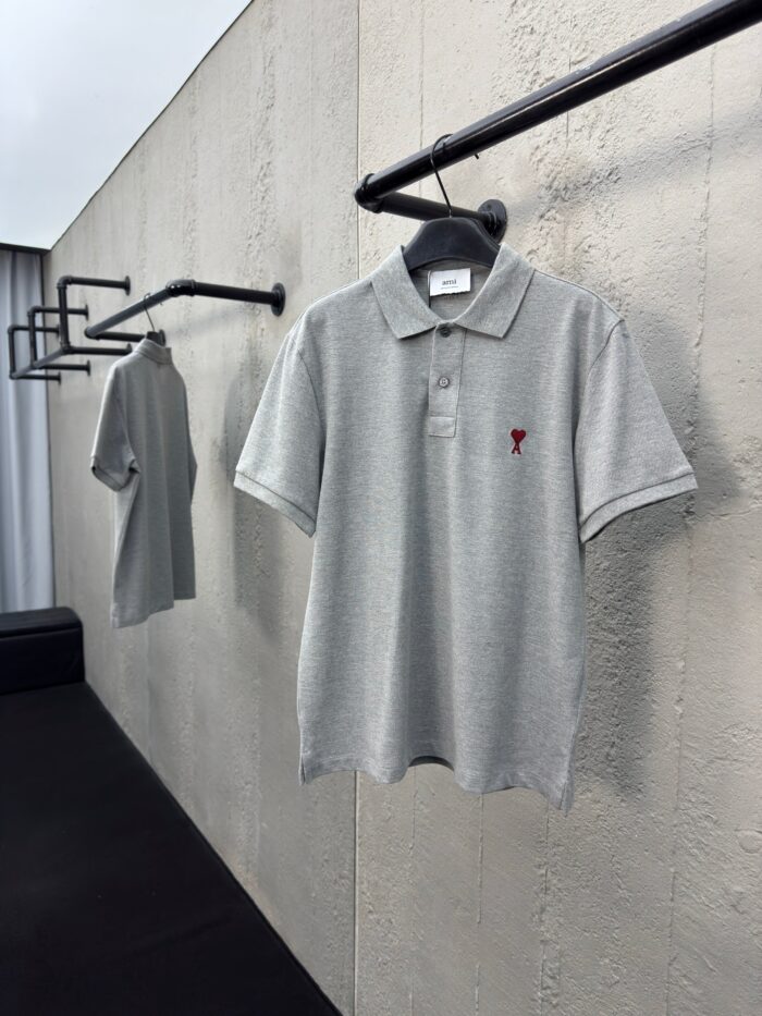 Polo grigie eleganti su supporto minimalista, stile classico e dettagli raffinati in vetrina moderna.