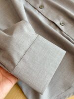 Polsino di camicia grigia elegante, dettaglio di qualità e stile moderno.