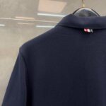 Maglietta polo navy con dettaglio a righe sul retro del colletto, stile classico ed elegante.