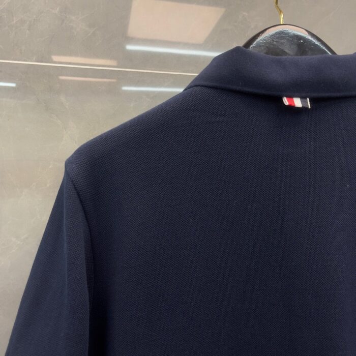 Maglietta polo navy con dettaglio a righe sul retro del colletto, stile classico ed elegante.
