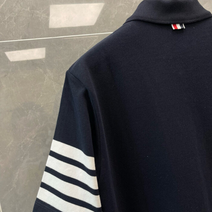 Poloshirt navy con strisce bianche e logo storico, stile sportivo ed elegante.