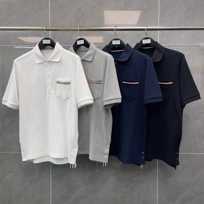 Set di polo classiche neutre: bianco, grigio, navy e nero su sfondo grigio chiaro.