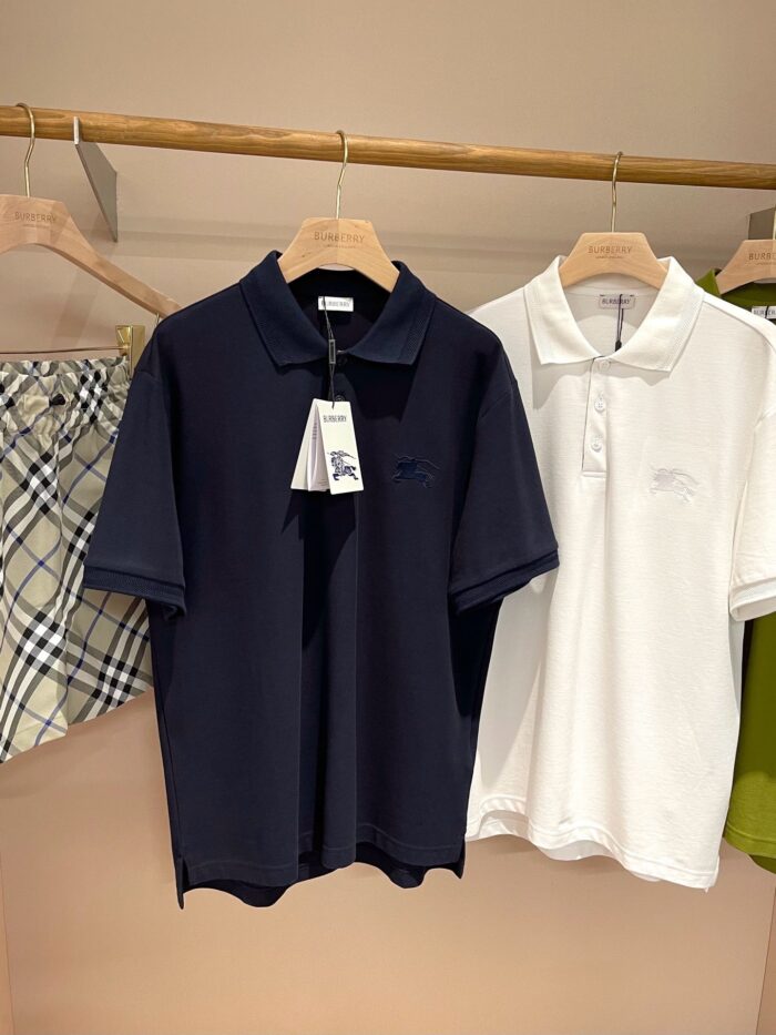 Magliette polo classiche navy e bianca in esposizione elegante su rastrelliera in legno.