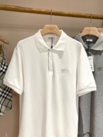 Esposizione di polo classiche in tessuti naturali su appendiabiti in legno.