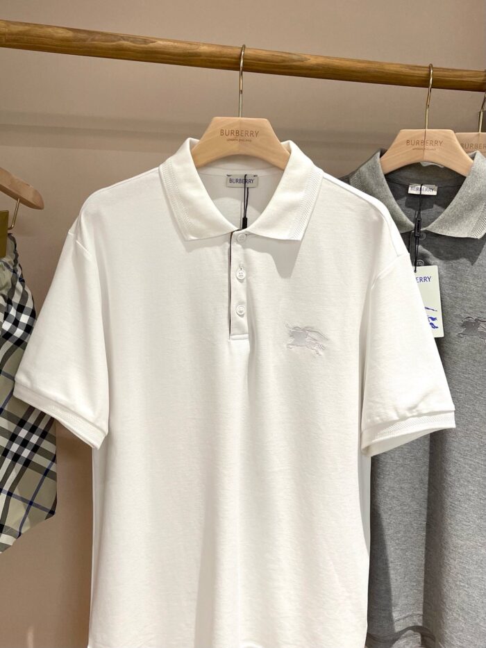 Esposizione di polo classiche in tessuti naturali su appendiabiti in legno.