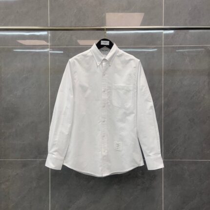 Camicia bianca classica con colletto button-down su sfondo grigio elegante.