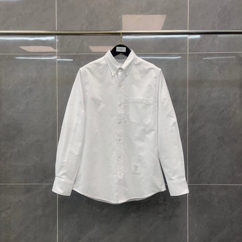 Camicia bianca classica con colletto button-down su sfondo grigio elegante.