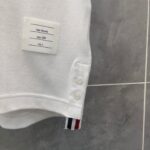 Polo bianca classica con badge a strisce rosse, bianche e blu, dettagli di qualità.