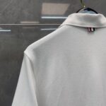 Maglietta polo bianca con logo a bande colorate, stile classico e tessuto traspirante.
