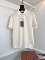Maglia polo bianca elegante su appendino con borsa cognac, stile versatile e look raffinato.