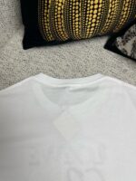 Maglietta bianca casual con tag, decorazione moderna e sfondo elegante con cuscino geometrico.