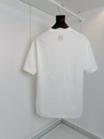 T-shirt bianca semplice, senza toppe o dettagli, su appendiabiti minimalista per look versatile.