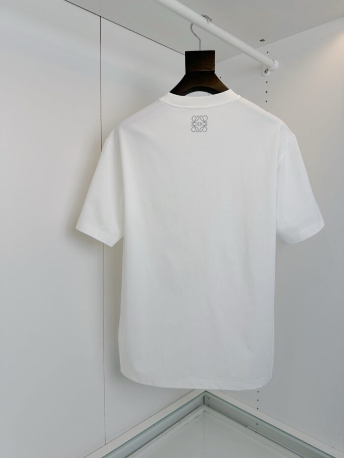 T-shirt bianca semplice, senza toppe o dettagli, su appendiabiti minimalista per look versatile.