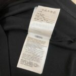 Etichetta cura abbigliamento nero con istruzioni multilingue e simboli, resistente e ben visibile.