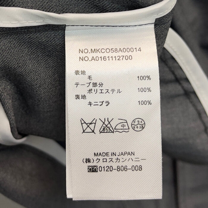 Etichetta di cura abbigliamento giapponese con codici, materiali e supporto clienti.