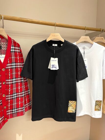 Vetrina streetwear con T-Shirt nera, cardigan a quadri e T-Shirt bianca su supporto di legno.