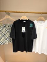Esposizione di abbigliamento casual: T-shirt nere e bianche con shorts a quadri beige e nero.