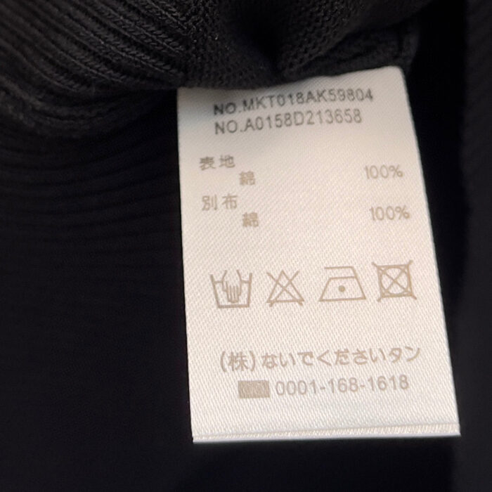 Etichetta con istruzioni di cura e composizione in cotone e sintetico, accessori di qualità.