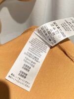 Etichetta di cura per top beige in tessuto sintetico con simboli e QR code.