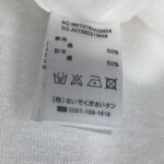 Etichetta abbigliamento con istruzioni di cura, materiali e numeri seriali.