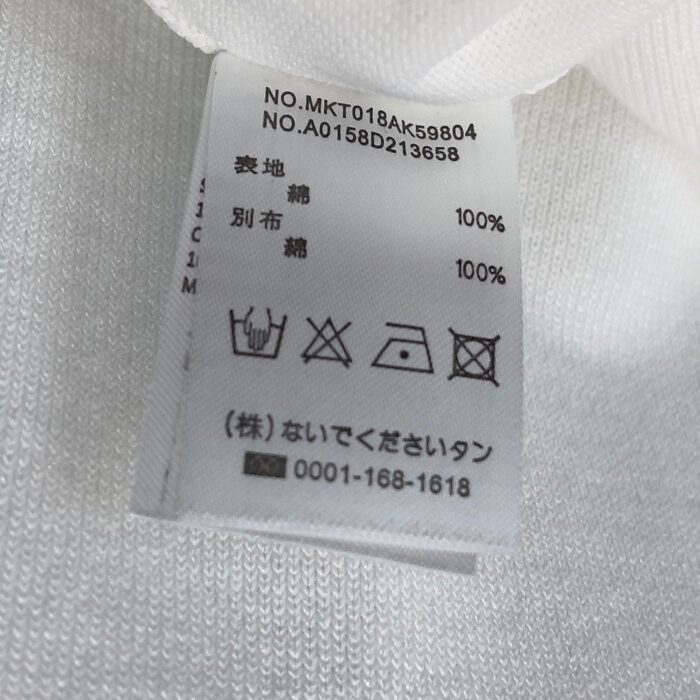 Etichetta abbigliamento con istruzioni di cura, materiali e numeri seriali.