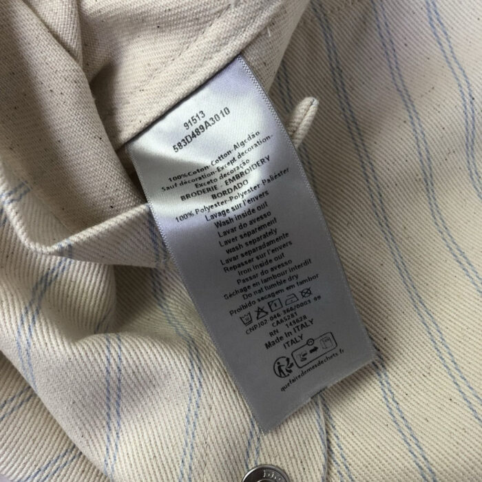 Dettaglio di abbigliamento in lino con etichetta e bottoni metallici.