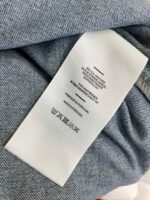 Etichetta di cura su jeans di denim chiaro con simboli e istruzioni di lavaggio.