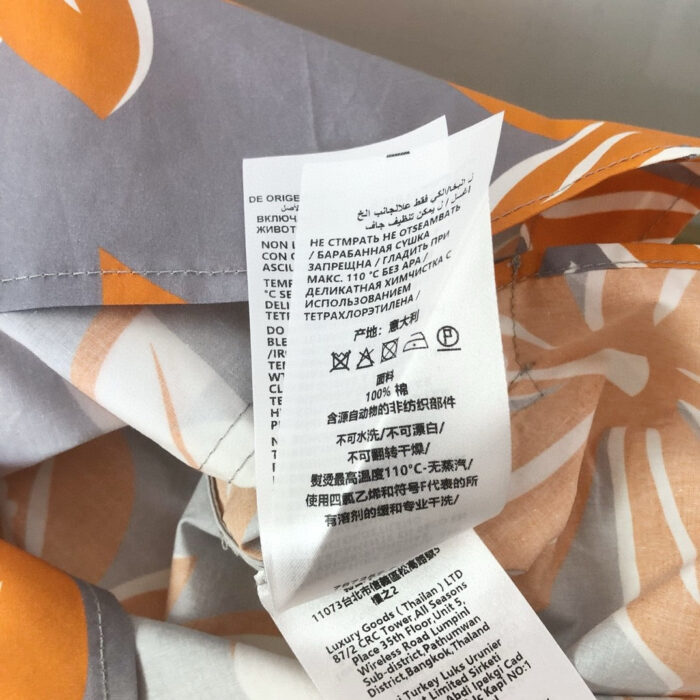 Etichetta di cura su abbigliamento con motivo astratto in grigio e tonalità calde.