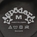 Etichetta di abbigliamento Spooder, taglia M, produzione a Los Angeles, simboli di cura.
