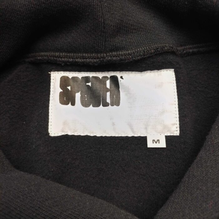 Etichetta di maglia sportiva nera con logo bianco e tag taglia M, stile urbano e trendy.