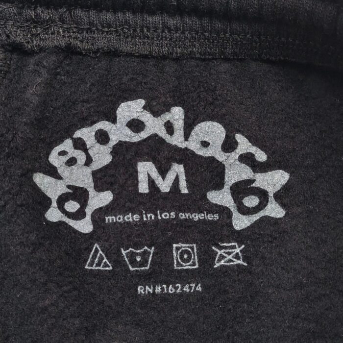 Etichetta moda Spoder, taglia M, Made in Los Angeles, con simboli di cura tessuto.