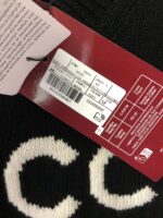 Etichetta rossa e maglione con lettere bianche, dettagli di stile e cura.