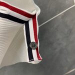 Dettaglio del colletto con strisce colorate e bottoncino in stile casual elegante.