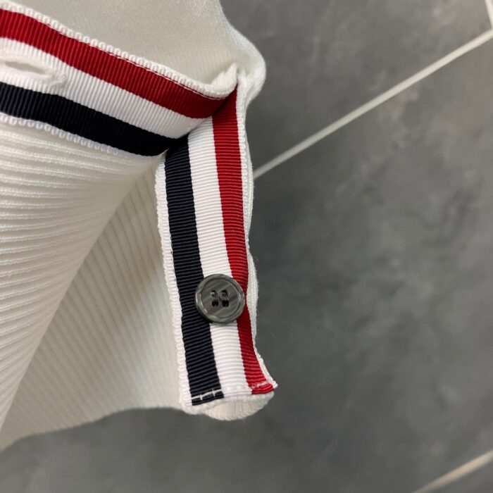 Dettaglio del colletto con strisce colorate e bottoncino in stile casual elegante.