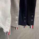 Polo in gradiente con polsini a righe rosse, bianche e blu, stile casual elegante.