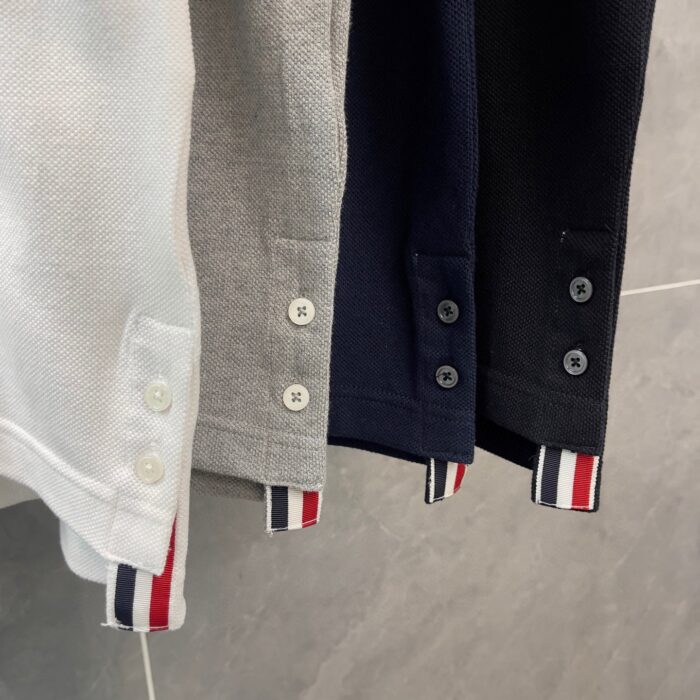 Polo in gradiente con polsini a righe rosse, bianche e blu, stile casual elegante.