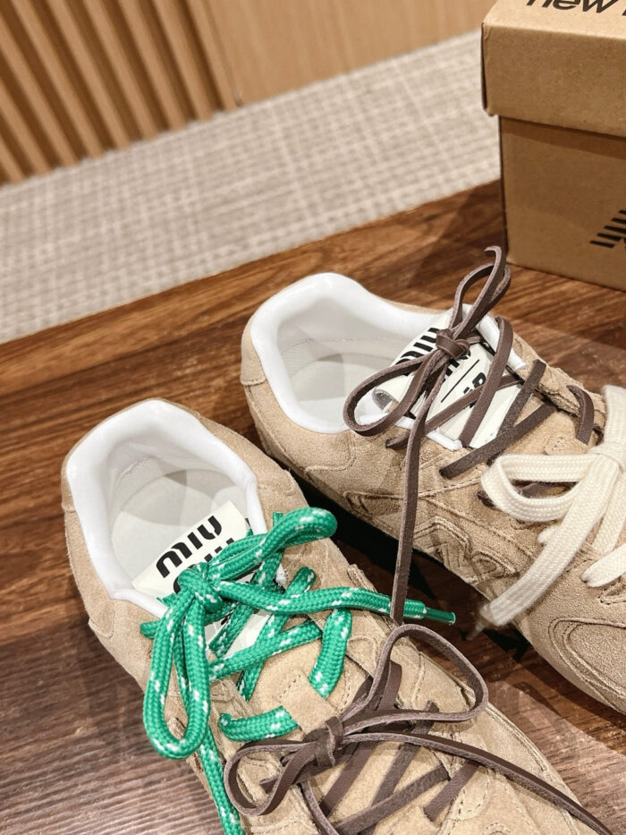Sneaker beige con lacci colorati e suola bianca su superficie in legno elegante.
