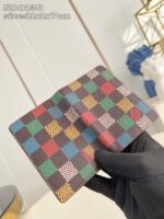 Portafoglio elegante con pattern a quadri colorati, maneggiato con guanto in contesto moderno.
